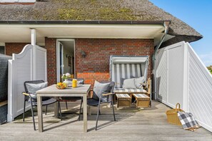 A covered outdoor seating area with a table, chairs, and a bench. - Watt Apartment, right on Rantum Bay on Sylt (Sylt)