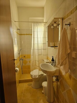 A bathroom with a shower, toilet, sink, and a towel hanging on the wall. - Sky Line Penthouse Apartment (Trikala)