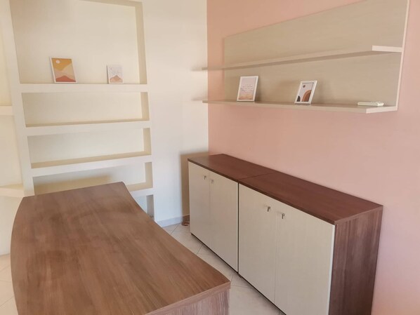 A room with a wooden table, white cabinets, and shelves with framed pictures. - Sky Line Penthouse Apartment (Trikala)