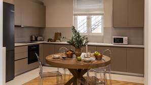 Een moderne keuken met een ronde eettafel, transparante stoelen en een potplant.