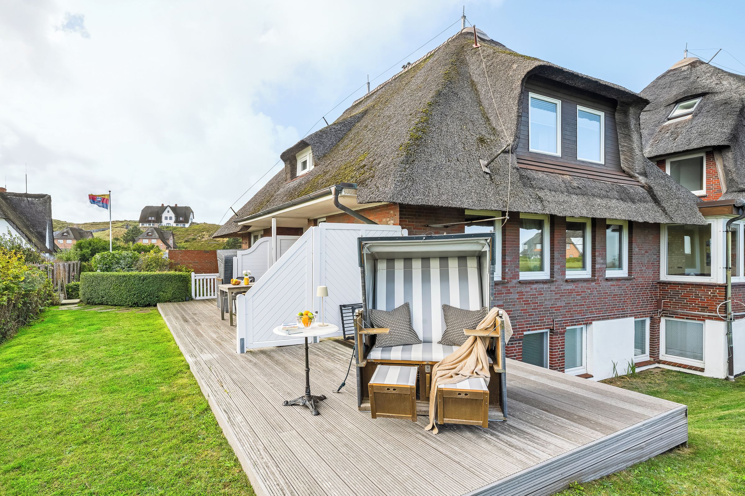 Ein Haus mit Strohdach, einer Terrasse mit Gartenmöbeln und Blick auf die Umgebung.