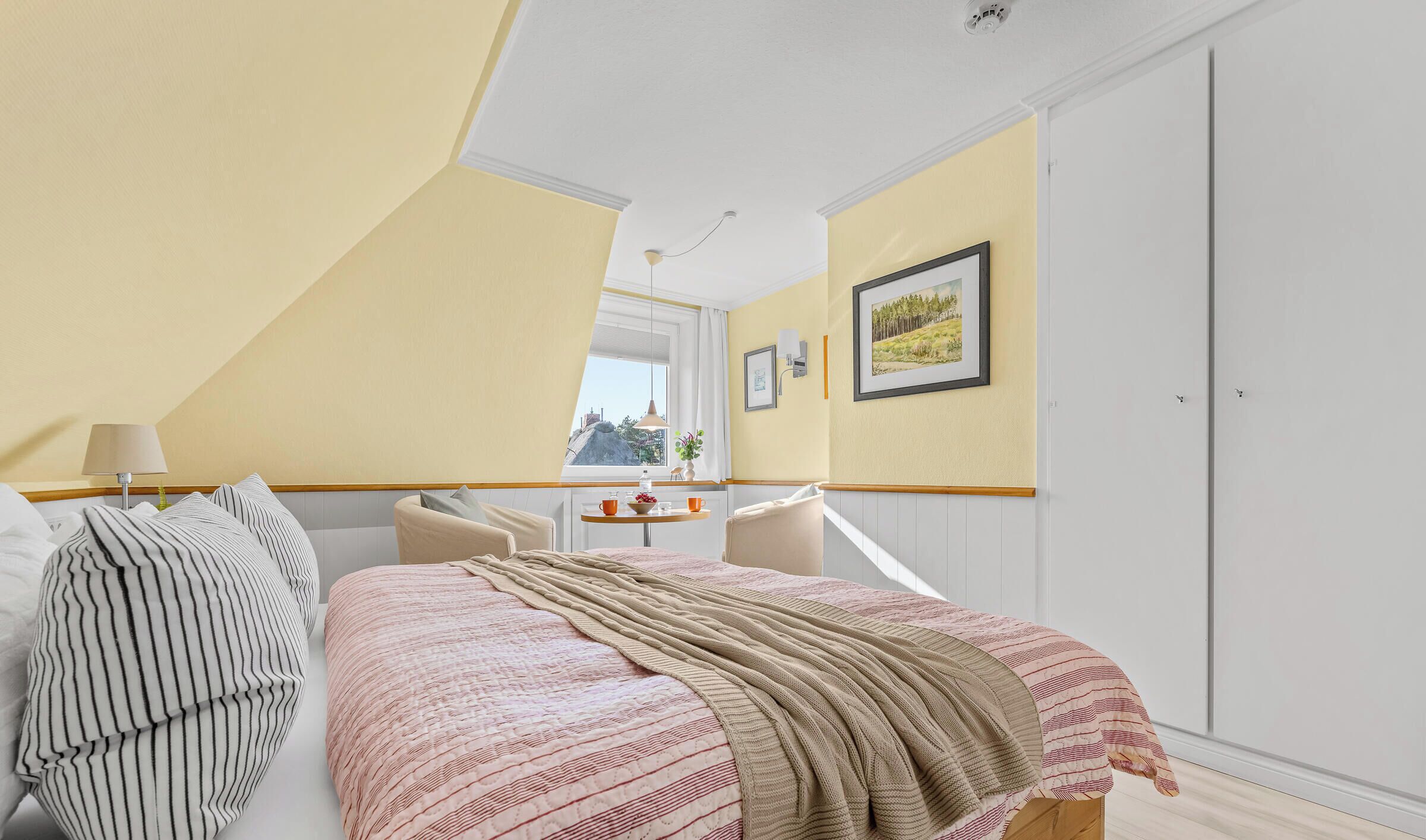 A bedroom with a bed, bedside table, chair, and a window with a view.