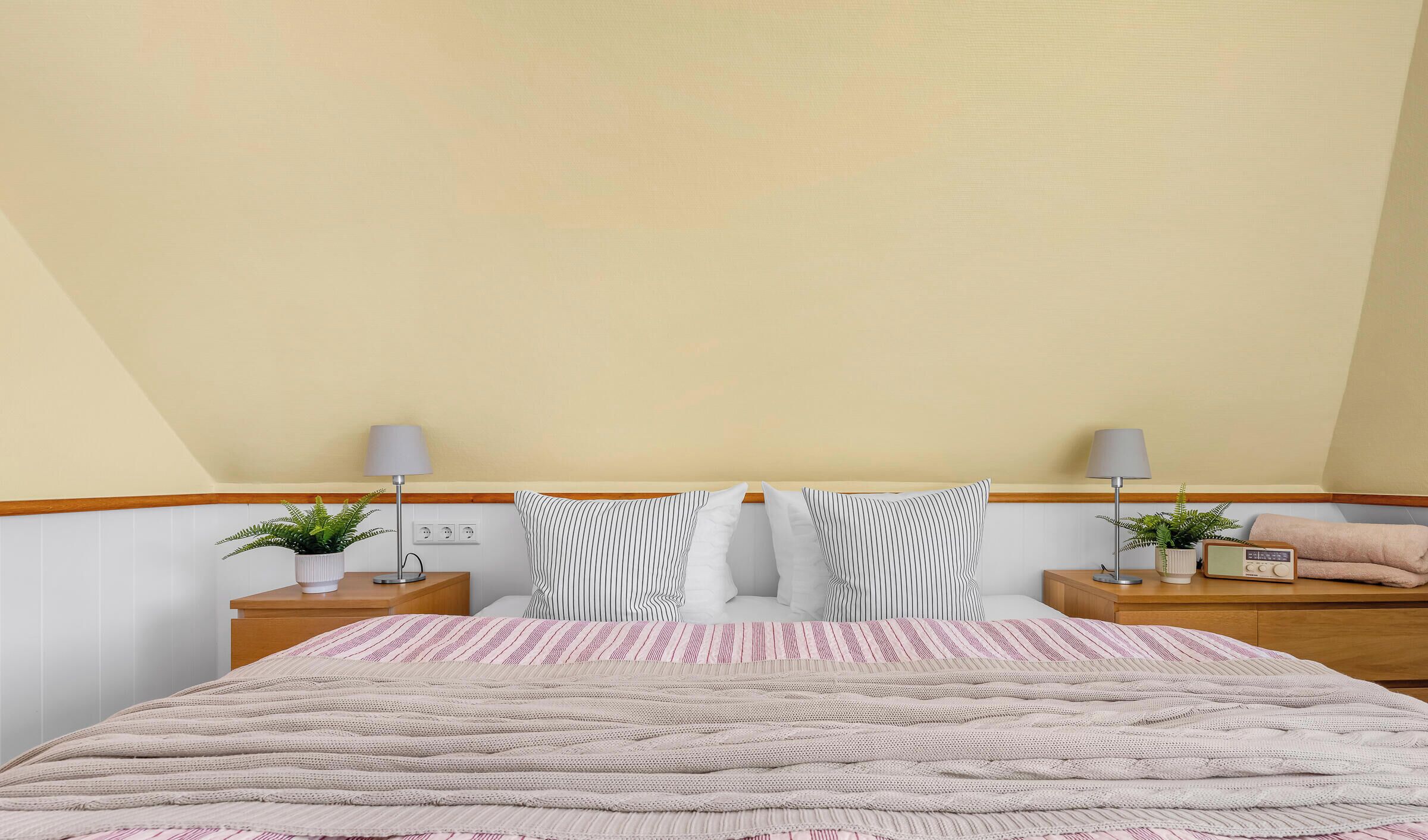 Ein Schlafzimmer mit einem Bett, zwei Nachttischen, Lampen und einem Radio.