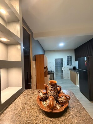 A kitchen with a granite countertop, a refrigerator, and a window.
