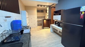 A modern kitchen with a built-in gas stove, a black refrigerator, and a blue water dispenser. - Comfortable house in Adrianopolis (Manaus)