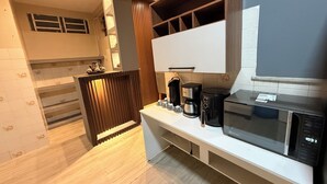 A modern kitchen with a microwave, coffee maker, and a wooden cabinet. - Comfortable house in Adrianopolis (Manaus)