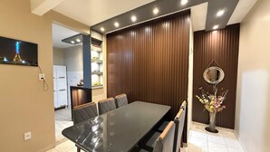 A dining area with a long table, chairs, a wall-mounted shelf with toys, a mirror, and a vase with flowers. - Comfortable house in Adrianopolis (Manaus)