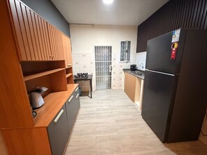 A kitchen with a wooden cabinet, a black refrigerator, and a tiled backsplash.