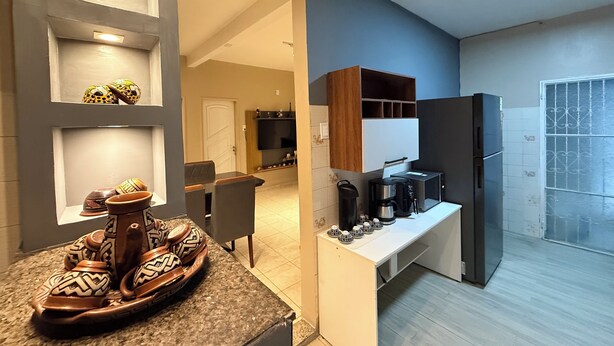 A modern kitchen with built-in appliances, a dining area with a table and chairs, and decorative pottery on the counter. - Comfortable house in Adrianopolis (Manaus)