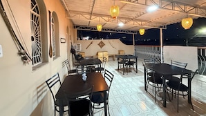 An outdoor dining area with multiple tables and chairs, a high ceiling with exposed beams, and decorative hanging lights. - Comfortable house in Adrianopolis (Manaus)