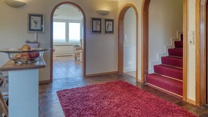 A spacious hallway with a red carpet, wooden arches, and a staircase with red carpet steps. - Apartment Emma directly on the mudflats in Rantum on Sylt (Sylt)