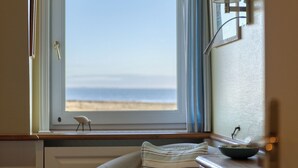 A room with a view of the beach, a small table with a bowl, a chair, and a lamp. - Apartment Emma directly on the mudflats in Rantum on Sylt (Sylt)