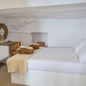 Une chambre à coucher avec un lit, une chaise, une petite table et un miroir.