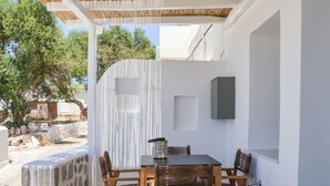 An outdoor patio with a table and chairs, a pergola overhead, and a stone wall. - Dream on  Adamas Milos (Adamas)