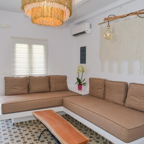 A modern living room with a large L-shaped sofa, a wooden bench, and a hanging light fixture. - Dream on  Adamas Milos (Adamas)