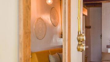 Una stanza accogliente con soffitto in legno, una panca bianca con cesti intrecciati e un lampadario.