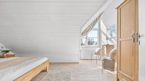 A bedroom with a wooden bed, a bench, a chair, a wardrobe, and a window with curtains. - Modern beachfront apartment in Stein with exceptional sea view and terrace (Stein)