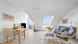 A spacious loft with a high ceiling, a dining area with a table and chairs, a sofa with cushions, and a large skylight. - Modern beachfront apartment in Stein with exceptional sea view and terrace (Stein)