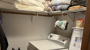 Une buanderie équipée d’un lave-linge, d’un sèche-linge et d’étagères au-dessus pour le rangement.