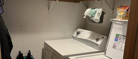A laundry room with a washing machine, dryer, and shelves above for storage.
