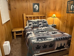 A wooden cabin room with a bed, a bench, and a lamp. - Moose`s Caboose | Hot Tub | Near Yellowstone (Island Park)