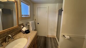 Une salle de bain équipée d’un lavabo, d’un miroir, d’un porte-serviettes et d’un espace douche.