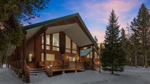 A log cabin with a large porch, multiple windows, and a snow-covered landscape. - Paradise in the Pines | Hot Tub | 35 miles to YNP (Island Park)