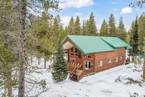 Eine Holzhütte mit grüner Dachbegrünung, umgeben von Schnee und Bäumen.