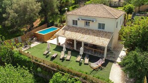 Ein zweistöckiges Haus mit Ziegeldach, Swimmingpool und überdachter Terrasse mit Gartenmöbeln.