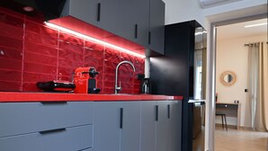 Una cocina moderna con gabinetes grises, encimera roja y refrigerador negro.