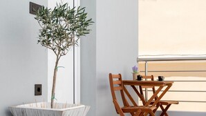 Un balcón con mesa y sillas de madera, una planta en maceta y una ventana con vistas.
