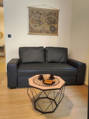 A dark grey sofa with two cushions, a hexagonal table with a decorative tray, and a vintage world map on the wall. - Calliope's Rhapsody Luxury Apt-Center of Rhodes (Rodos)