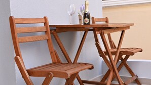 Un conjunto de mesa y sillas de madera frente a una pared blanca, con una botella y un vaso sobre la mesa.