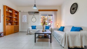 A living room with a sofa set, a coffee table, a bookshelf, and a wall clock. - Mike's House in Kremasti near the Beach Rhodes (Kremasti)