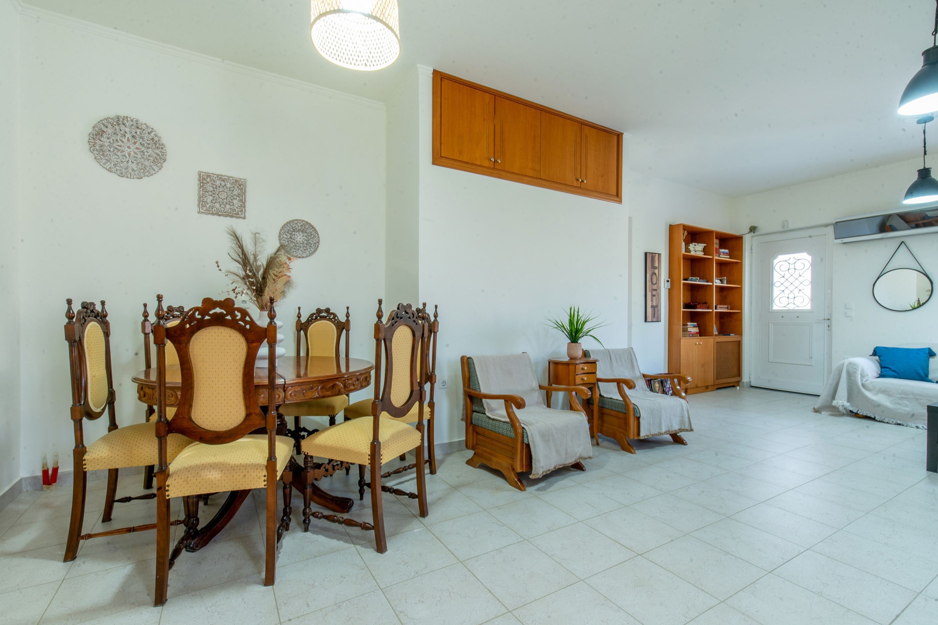 A spacious living area with a dining table, chairs, a sofa, and a bookshelf.