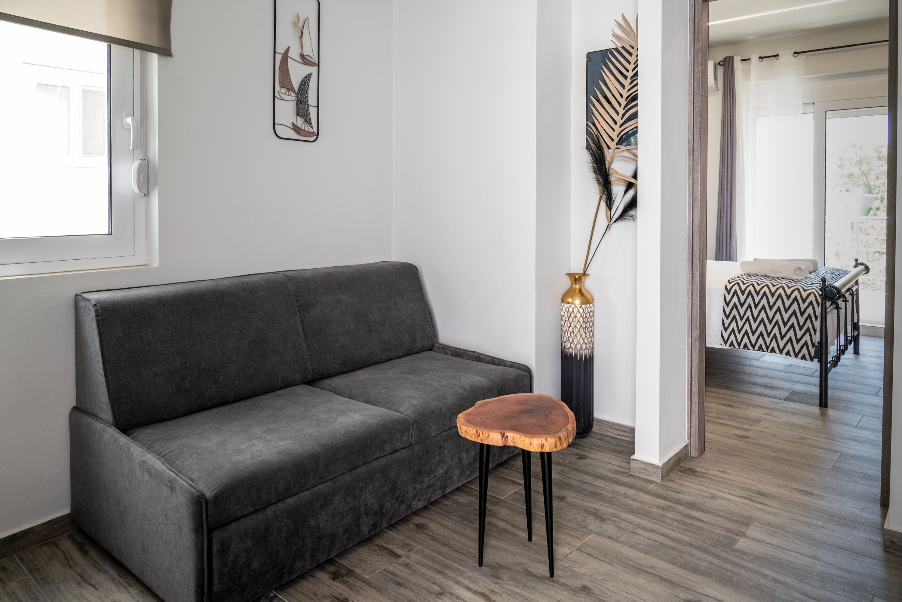 A modern living room with a grey sofa, a wooden side table, and a decorative vase.