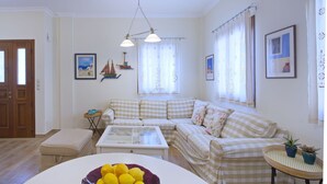 Een woonkamer met een geruit bankje, een bijzettafeltje en een klein tafeltje met planten.