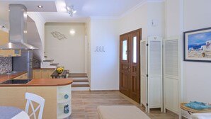 Een moderne keuken met een centraal eiland, een eethoek met een tafel en stoelen, en een trap die naar een verdieping leidt.