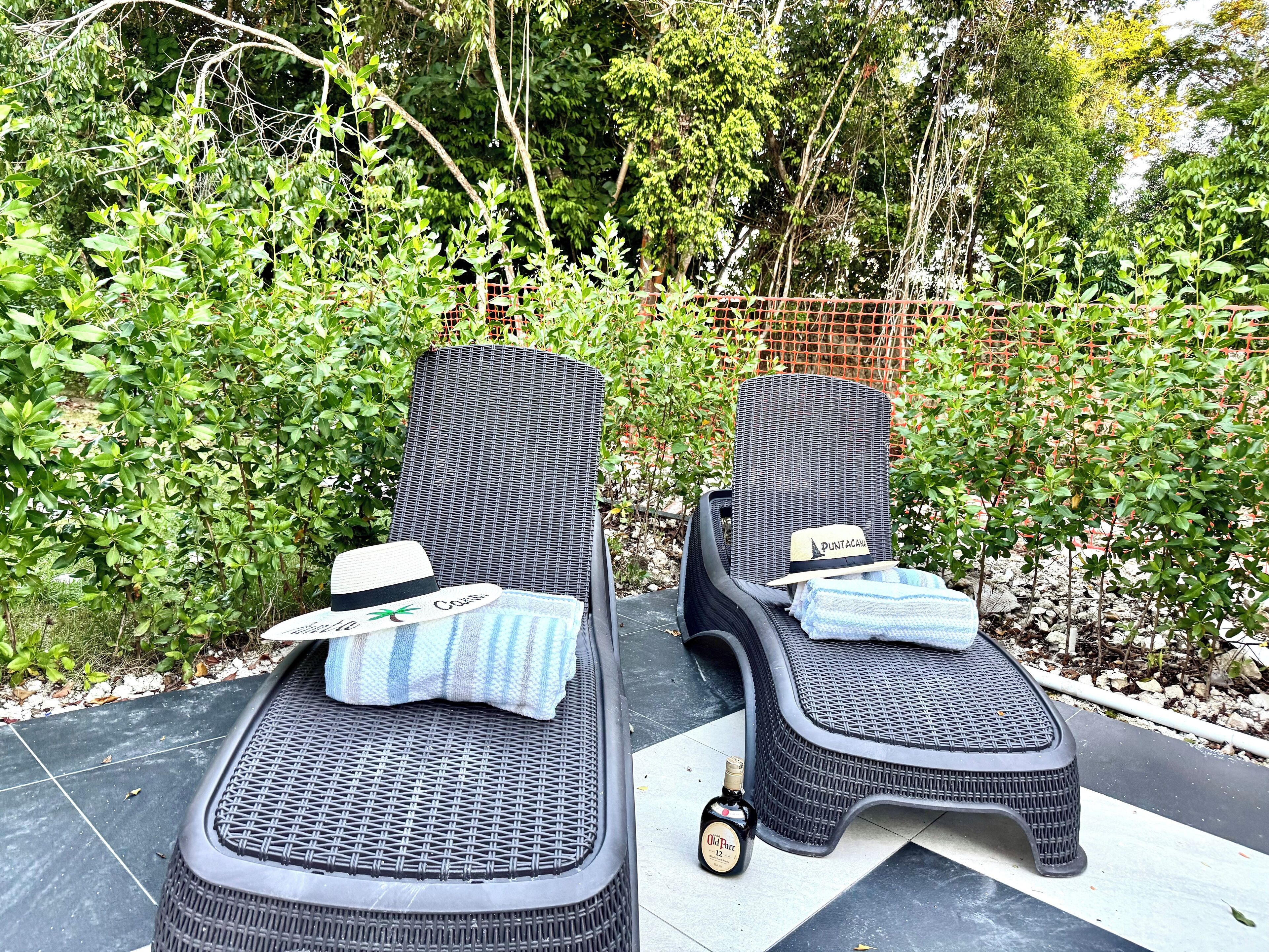Two outdoor lounge chairs with a woven seat and backrest, placed on a tiled patio.