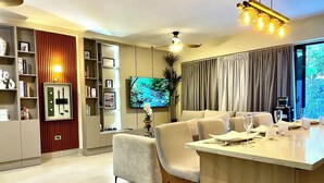 Una sala de estar moderna con un sofá, un comedor con mesa, y un televisor montado en la pared.