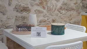 A stone wall, a clock, a table with chairs, a sign, and a lamp. - [Bracket] in Heraklion (Heraklion)