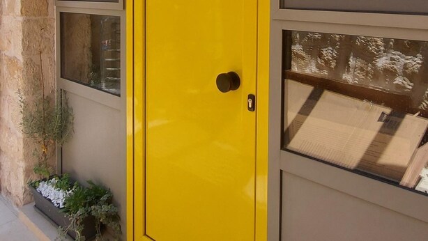 A yellow door with a small window and a doorbell. - [Bracket] in Heraklion (Heraklion)