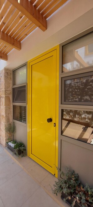 A yellow door with a small window and a doorbell. - [Bracket] in Heraklion (Heraklion)