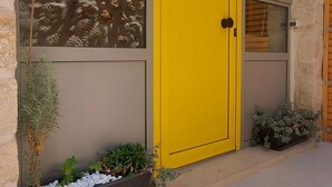 A building with a yellow door, large windows, and potted plants. - [Bracket] in Heraklion (Heraklion)