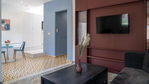 Ein modernes Wohnzimmer mit einem Flachbildfernseher an einer roten Wand, einem dunklen Couchtisch mit einer Vase und einem gemusterten Teppich.