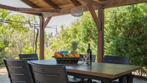 Eine Terrassengruppe im Freien mit Holztisch und -stühlen, umgeben von üppiger Bepflanzung.