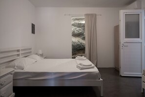 Une chambre à coucher avec un lit, une table de chevet, une fenêtre avec des rideaux et une porte.