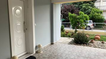 Un ingresso pulito e moderno con pavimento piastrellato, una porta bianca con maniglie circolari, una piccola pianta in vaso e un lanterna sul lato destro.