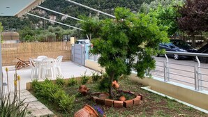 Una terrazza con mobili da esterno, un albero e vasi in terracotta.