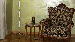 A room with a floral-patterned armchair, a lamp with a white shade, and a small table with a candle. - ALPHA OMEGA   suite (ΑΩ) (Thessaloniki)